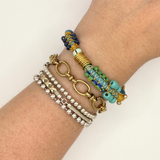 Close-up of a wrist wearing multiple colorful bracelets on a light background