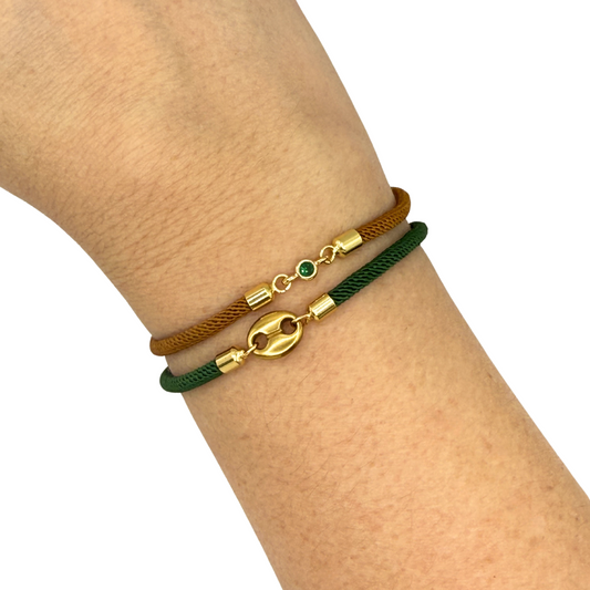 Two bracelets on a wrist, one brown and one green, with gold accents.