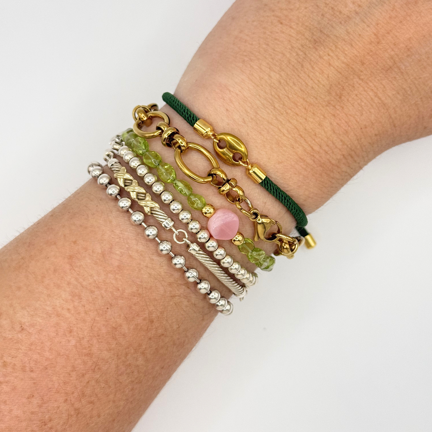 Wrist wearing multiple bracelets on a white background