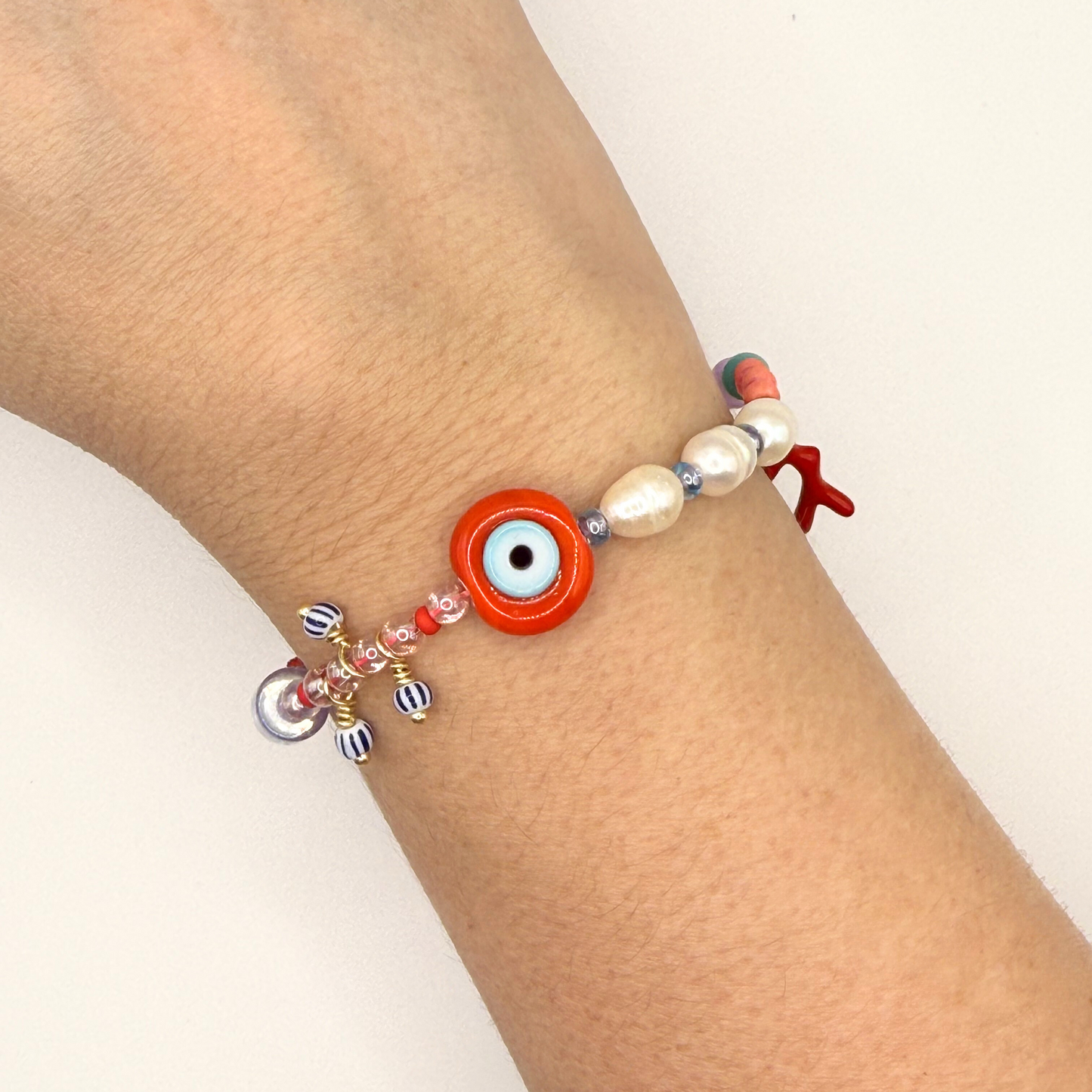 Beaded bracelet with an eye charm on a wrist against a white background

