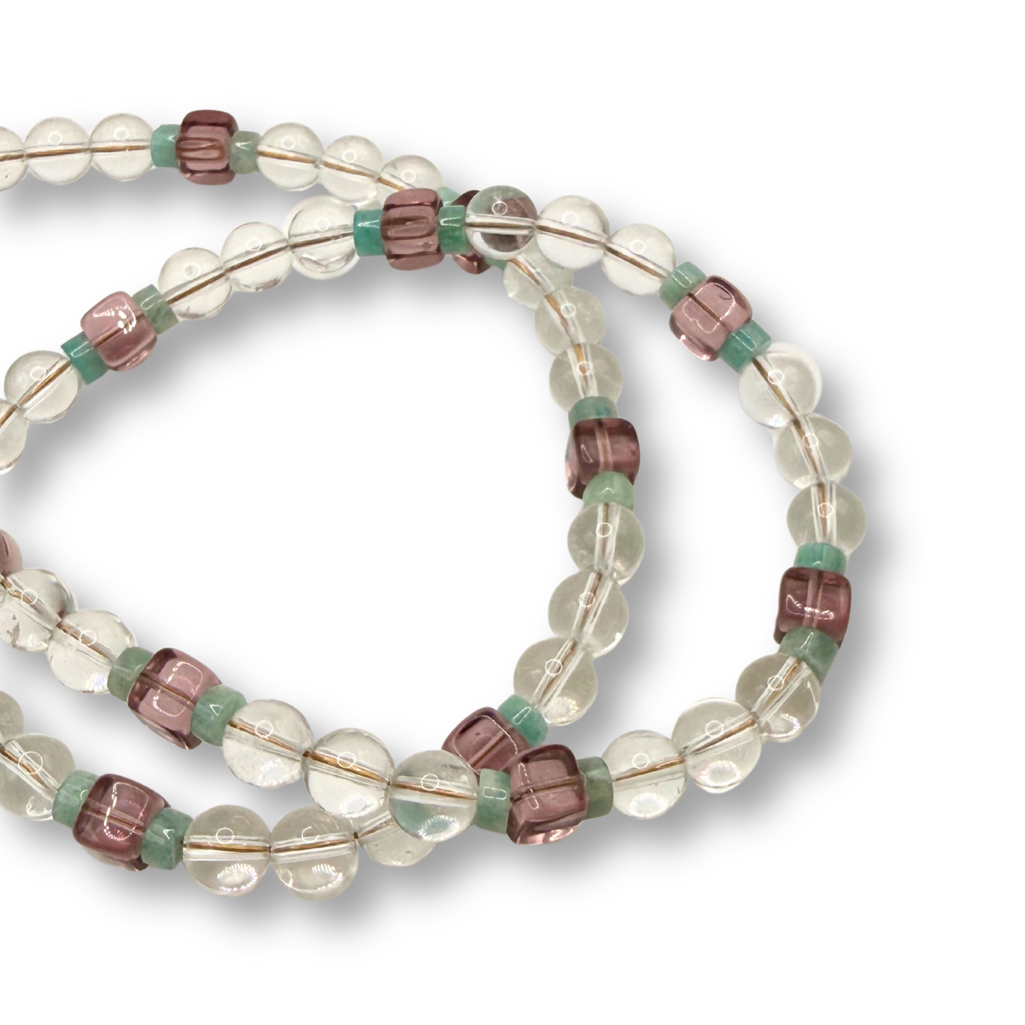 A beaded necklace made with clear glass beads with alternating translucent pinkish-brown and mint green spacer beads, coiled on a white background.